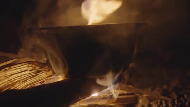 Las llamas de la fogata bajo la olla de cocción en la fogata en la cueva — Vídeos de Stock