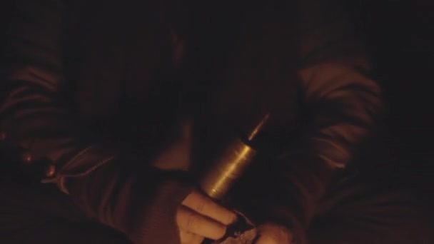 Człowiek wlewając ziarna kawy do szlifierki vintage przy ognisku w jaskini — Wideo stockowe