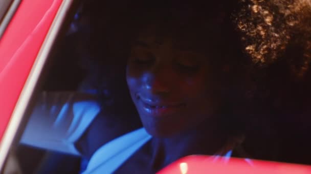 Женщина с афро, сидящая в водительском кресле красной машины — стоковое видео