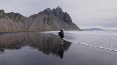 Sırt çantalı adam Vestrahorn Dağı 'ndaki ıslak sahilde