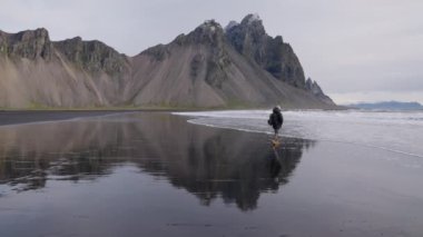 Sırt çantalı bir adam Islak plajda yürüyor Vestrahorn 'dan denize doğru