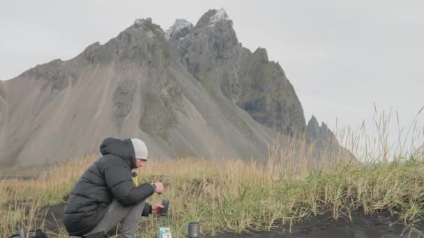 Homme préparant à boire en pleine nature autour de Vestrahorn Mountain — Video