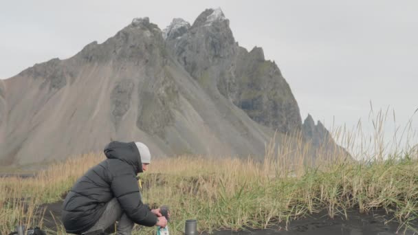 Человек, готовящийся пить в дикой местности вокруг горы Вестрахорн — стоковое видео
