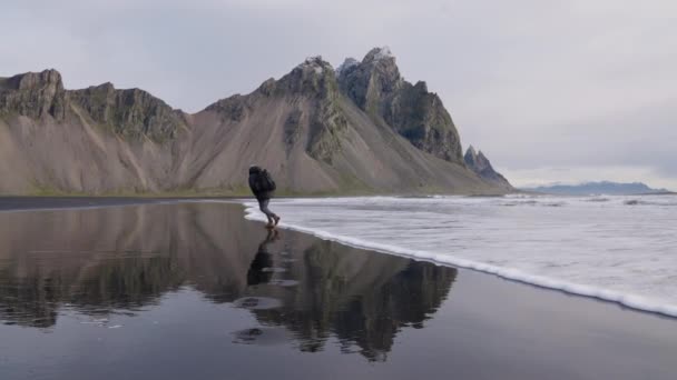 해변에서 얕은 바다를 떠다니는 삼각대를 든 사람 - 베스 트라 혼 — 비디오