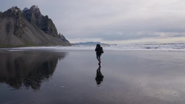 Hombre con mochila caminando por la playa húmeda hacia Vestrahorn — Vídeos de Stock