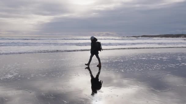 Hombre con mochila caminando a lo largo de la playa húmeda — Vídeos de Stock