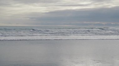 Wet Beach 'ten İzlanda Bulutlu Gökyüzü' nün altında dalgaların denize çakılışının geniş çaplı yavaş görüntüsü