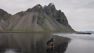İzlanda, Vestrahorn Dağı 'ndaki Black Sand Plajı' ndan kamerayla çömelmiş, el kamerasıyla çekilen yavaş çekim.