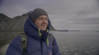 Mavi Giyen Gülümseyen Adam 'ın Sahil, İzlanda' dan Denizi Fotoğraflamak İçin Orta Yol Yavaş Çekimi