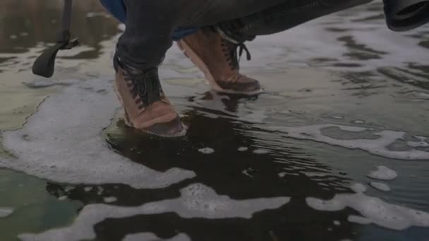 冰岛黑沙滩上蹲伏男子的中等慢镜头 他的脚步声蜿蜒而过 — 图库视频影像