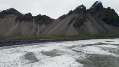 Wide Slow Motion İHA uçağı Black Sand Beach 'e ve Vestrahorn Mountain, İzlanda' ya doğru ilerliyor.