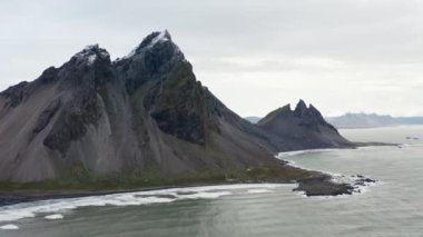 Geniş Yavaş Hareketli İHA Uçuşu Deniz Üzerinde, Kara Kum Kumsalı ve Vestrahorn Dağı, İzlanda
