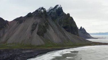 Geniş Yavaş Hareketli İHA Uçuşu Deniz Üzerinde, Kara Kum Kumsalı ve Vestrahorn Dağı, İzlanda