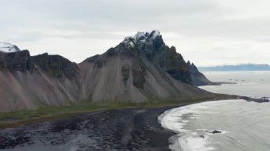 Geniş Yavaş Hareketli İHA Uçuşu Deniz Üzerinde, Kara Kum Kumsalı ve Vestrahorn Dağı, İzlanda