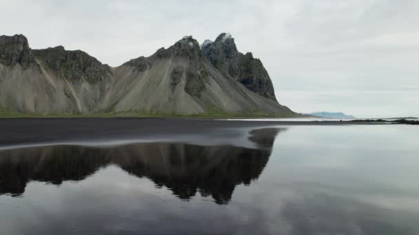 アイスランドのヴェストラホーン山から濡れた黒い砂のビーチの上の広いスローモーションドローン飛行 — ストック動画