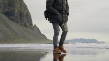 İzlanda 'daki Vestrahorn Dağı' ndan Siyah Kum Sahili 'nde Sırt çantalı Yürüyüşçünün Yavaş Hareketli Orta Çekimi