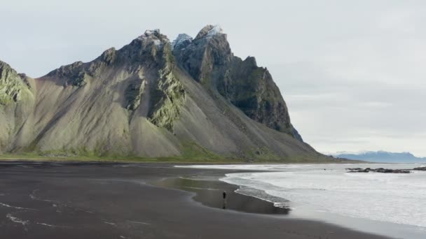 Slow Motion Arcing Drone Shot Man Black Sand Beach Tide — Wideo stockowe