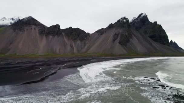 黒砂のビーチを越えてアイスランドのヴェストラホーン山に向かってドローンオーバー海とサーフ — ストック動画