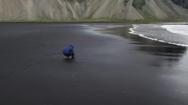 Arcing Slow Motion Wide Shot Photographer Crouching Camera Black Sand — Αρχείο Βίντεο