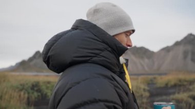 Vestrahorn Dağı yakınlarındaki Black Beach 'te kahve içen adam.
