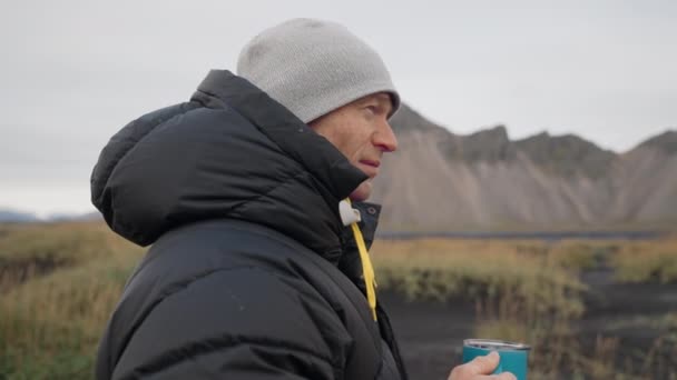 Hombre bebiendo café en playa negra cerca de la montaña Vestrahorn — Vídeo de stock