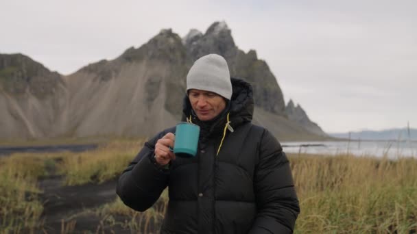 Mężczyzna pijący kawę na czarnej plaży w pobliżu Vestrahorn Mountain — Wideo stockowe