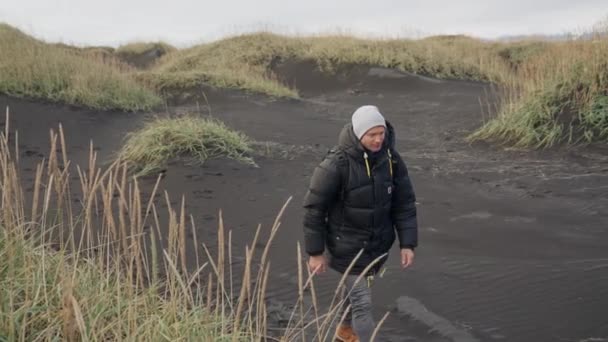 Uomo Escursioni sulla spiaggia di sabbia nera — Video Stock