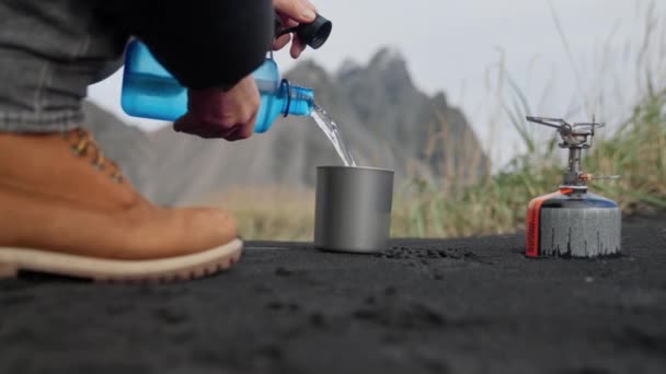 ガスキャンプストーブの横に水を入れる準備をする男 — ストック動画