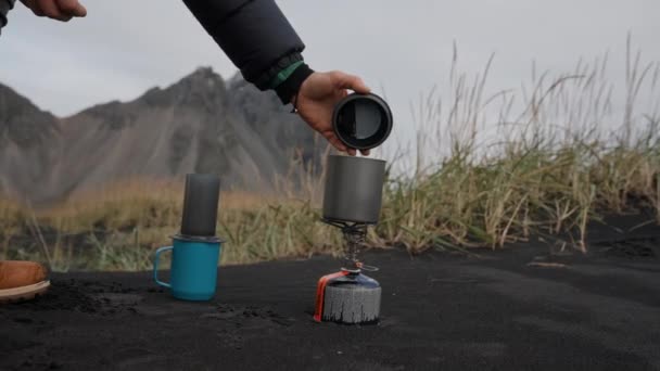 Man menghapus Lid From Cup On Camp Stove On Beach — Stok Video