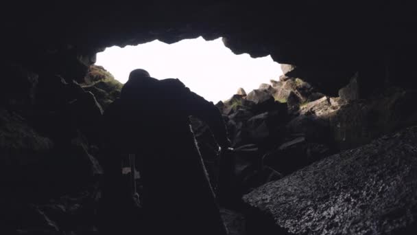 Man i lång rock med gitarr fall lämnar grotta — Stockvideo