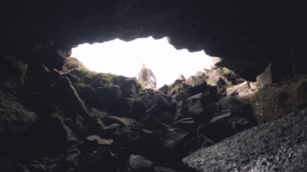 Man i lång rock med gitarr fall gå in i grottan — Stockvideo
