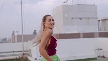 Şehrin çatısında dönen ve gülen genç bir kadın var.