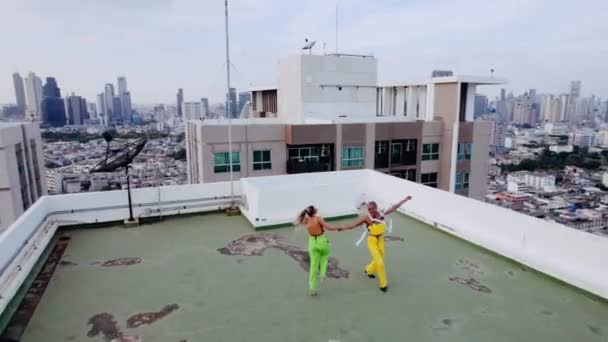 Drohnenaufnahmen von Modellen in Grün und Gelb, die auf dem Dach der Stadt tanzen — Stockvideo