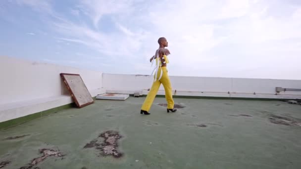 밝은 노란색 옷을 입은 댄서 가 도시의 옥상에서 춤을 추는 모습 — 비디오