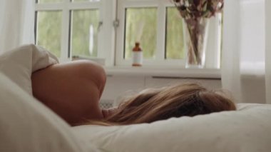 Sabahları yatağa uzanmış, pencereye bakan kadın.