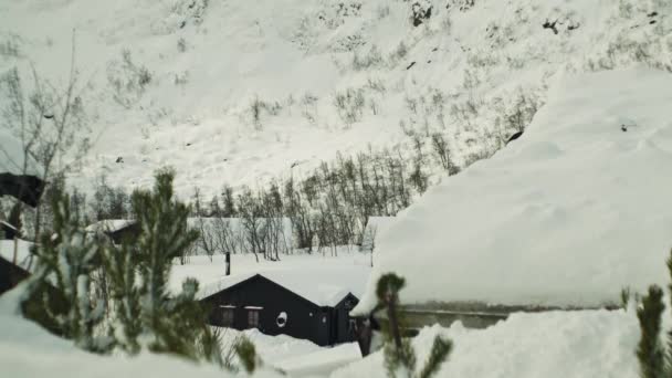 Hölzerne Gebäude unter schneebedeckter Berghälfte — Stockvideo