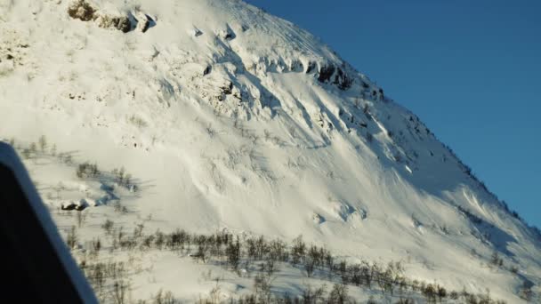 Pokryta śniegiem góra pod błękitnym niebem do drewnianych domów — Wideo stockowe