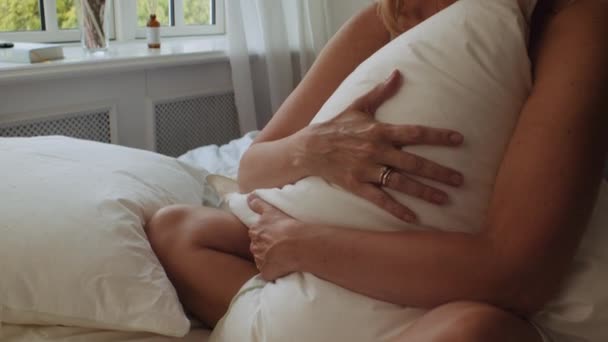 Kvinna Clutching kudde på sängen på morgonen och tittar bort — Stockvideo