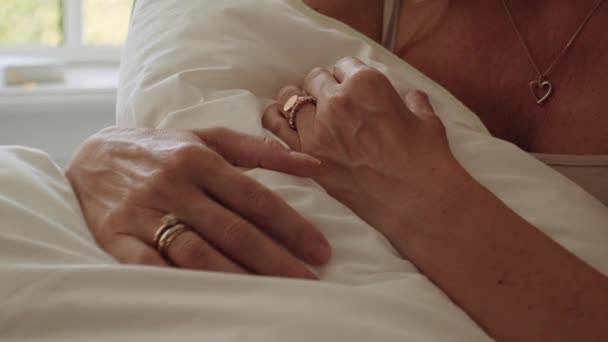 Frau mit Ringen an Fingern und Herz-Halskette Kupplungskissen im Bett — Stockvideo