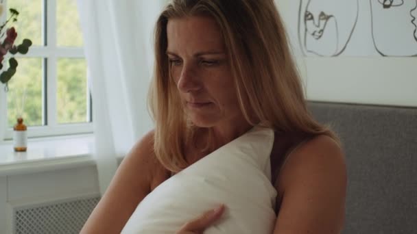 Frau kuppelt Kissen auf Bett am Morgen und schaut nach unten — Stockvideo
