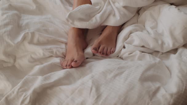 Ženské nohy s namalovanými nehty na nohou, jak leží v posteli — Stock video