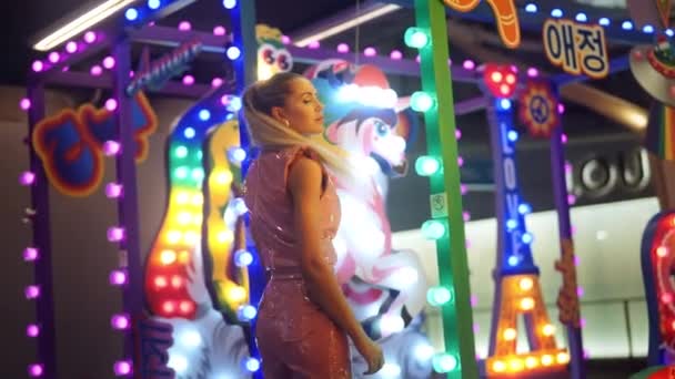Woman In Pvc Clubwear Posing Amongst Neon Fairground Lights — Stock Video