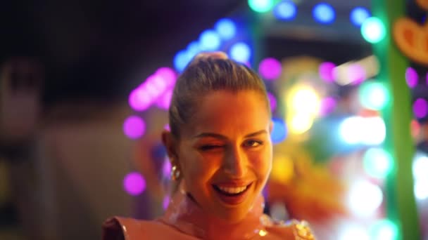 Vrouw glimlachen en knipperen naar camera wandelen tussen neon lichten — Stockvideo
