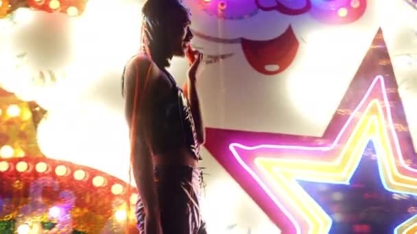 Man met rode paardenstaart en Pvc poseren door neon lichten — Stockvideo