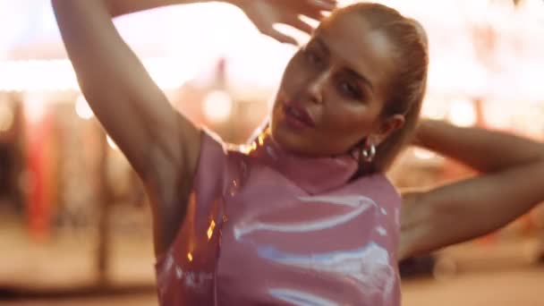 Žena v růžové Pvc Clubwear spinning a tanec na kameru podle neonu — Stock video