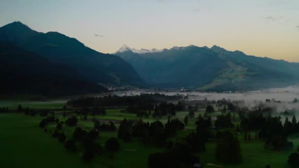 夜明けに山に見えるツェルの霧の風景の上にドローン — ストック動画