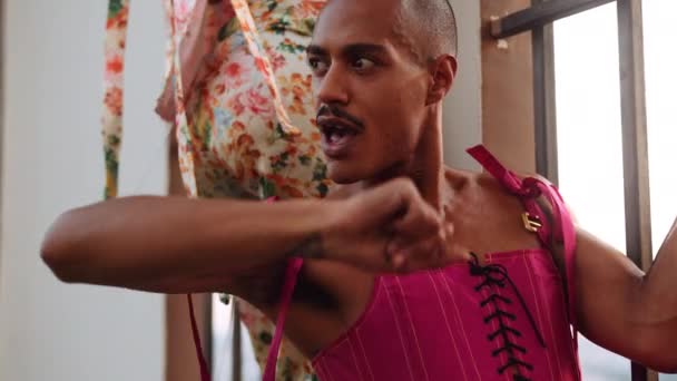 Dançarino masculino em corpete rosa por janela barrada olhando para a câmera — Vídeo de Stock
