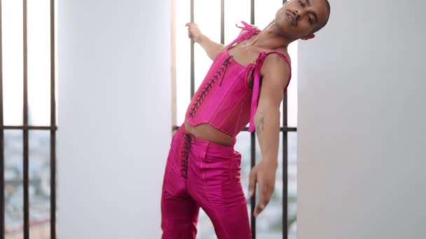 Dansende man in roze lijfje tegen versperd raam — Stockvideo