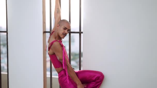 Dansende man in roze lijfje tegen versperd raam — Stockvideo