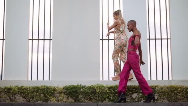 Чоловік в рожевому клубному одязі проходить повз молоду жінку танцює — стокове відео